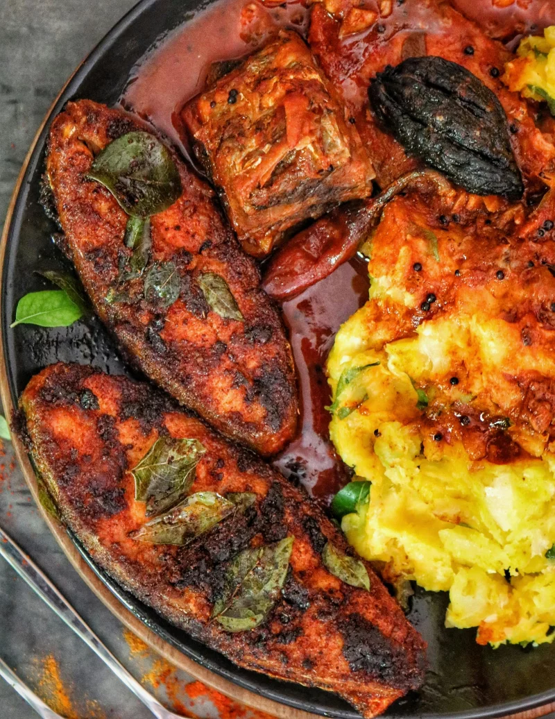 Delicious spicy fish served with mashed potatoes and savory sauce, garnished with fresh herbs.
