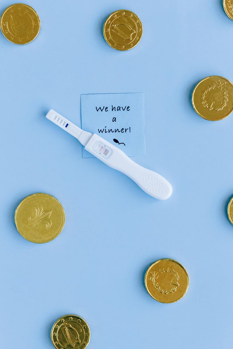 Positive pregnancy test with coins highlighting new beginnings and financial considerations.