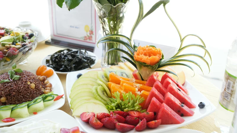Vibrant assortment of fresh fruits and salads beautifully arranged on a dining table.