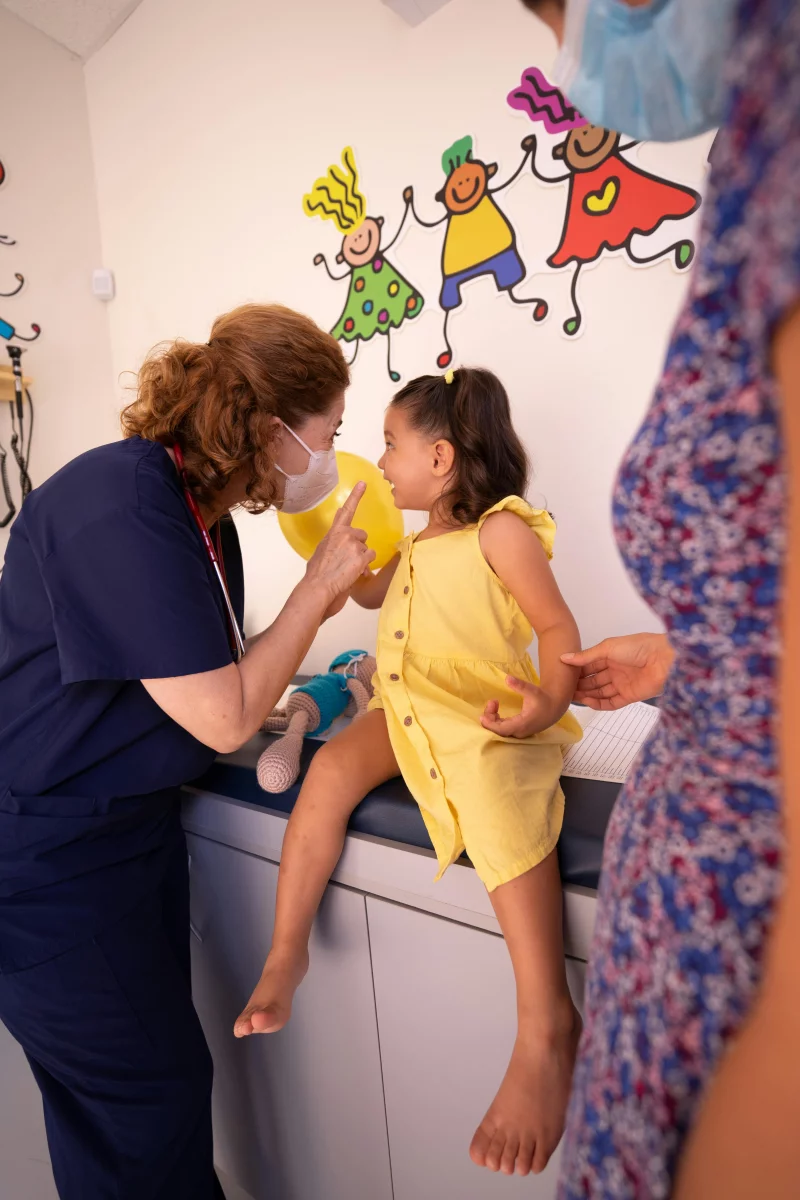 Nurse talking to a child in a bright pediatrician's office.