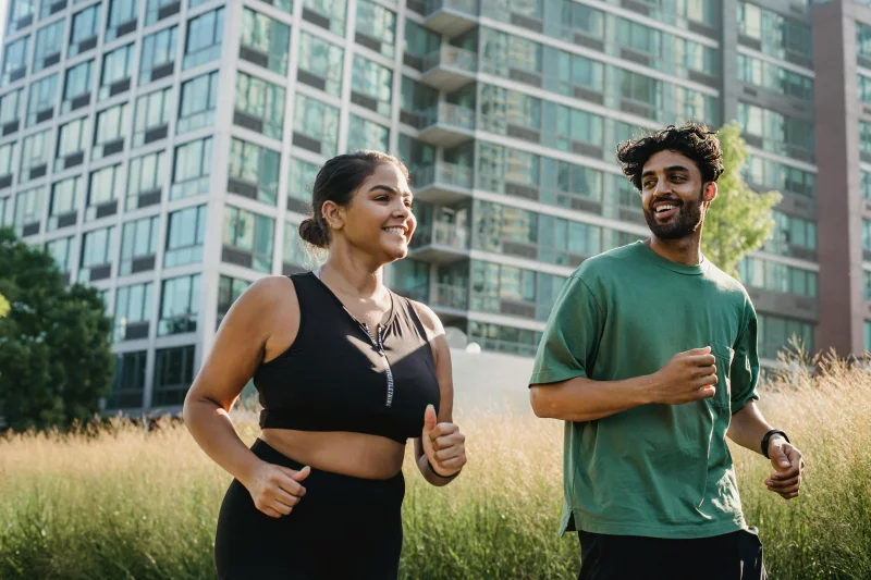 A joyful couple jogging in a city park, promoting a healthy lifestyle.