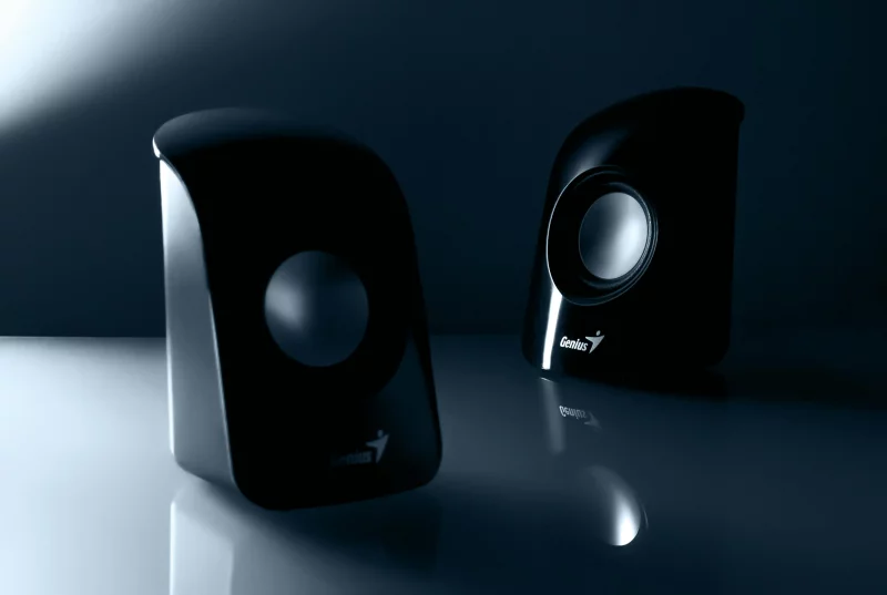 Stylish black desktop speakers with reflective design for enhanced audio experience.
