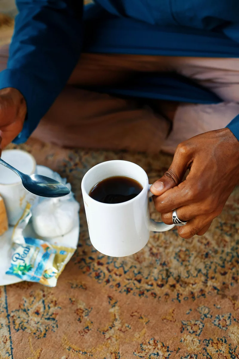 A person enjoying traditional coffee with sugar cubes in Abuja, Nigeria.