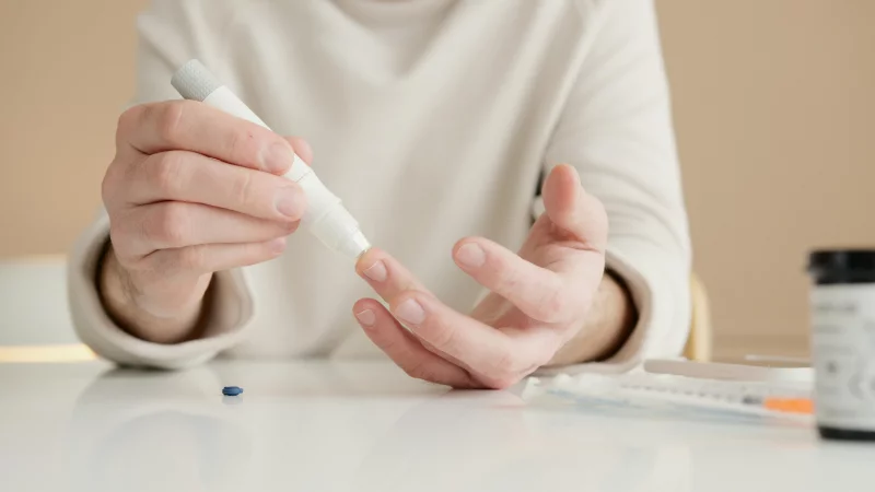 Close-up of a person using a glucometer to test blood sugar at home.