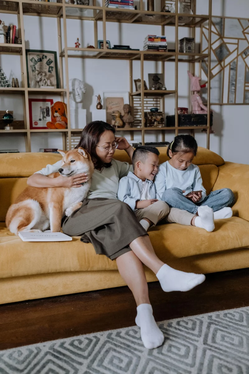 A warm family moment with an Asian mother, her children, and a Shiba Inu relaxing indoors.