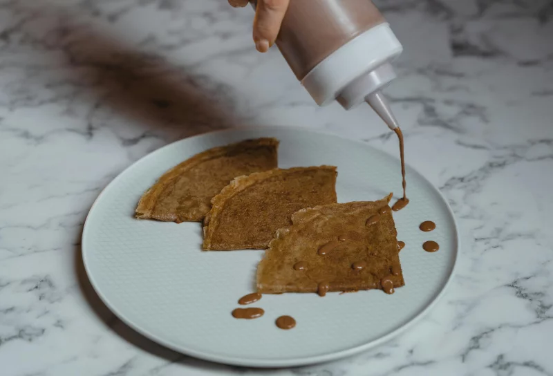 Savor the taste of freshly made crepes drizzled with rich chocolate sauce, perfect for a delightful treat.