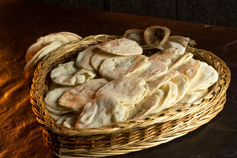 Rustic display of freshly baked flatbreads in a wicker basket, perfect for food photography.