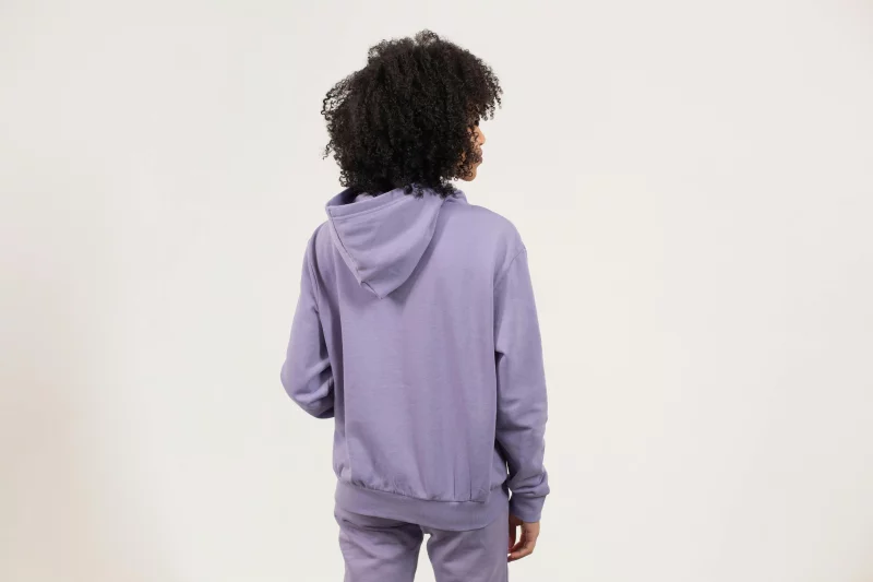 Back view of woman in purple hoodie with curly hair on white background.