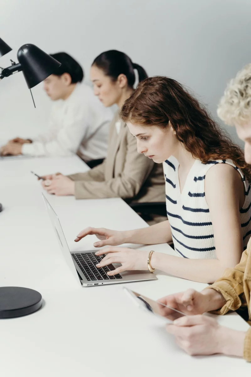 Diverse group of professionals working intently on laptops in a modern office.