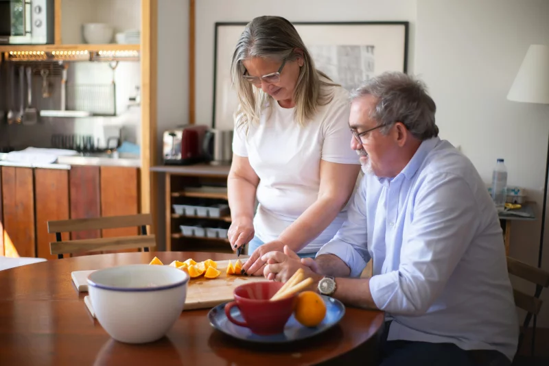 A couple enjoying preparing fresh oranges together in their cozy home kitchen setup.