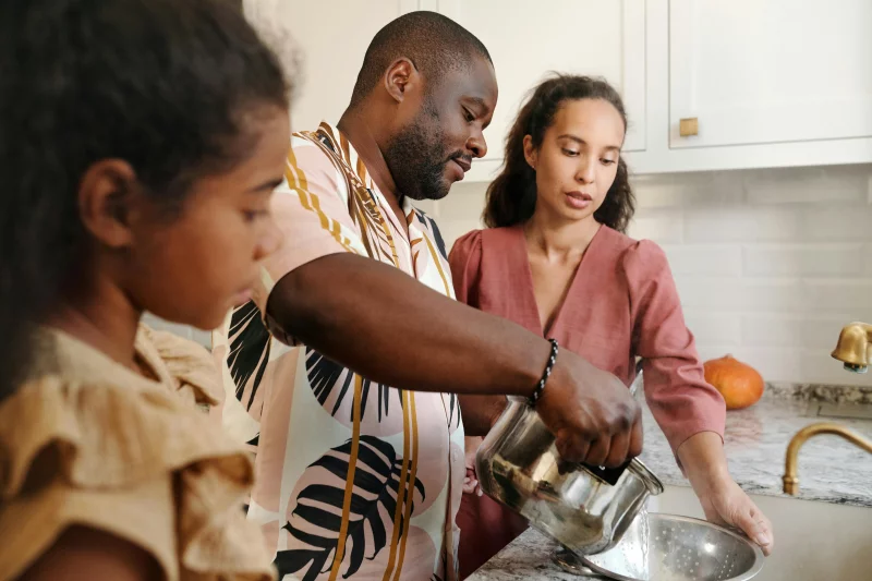 Family preparing meal together in a modern kitchen setting, showcasing teamwork and home cooking.