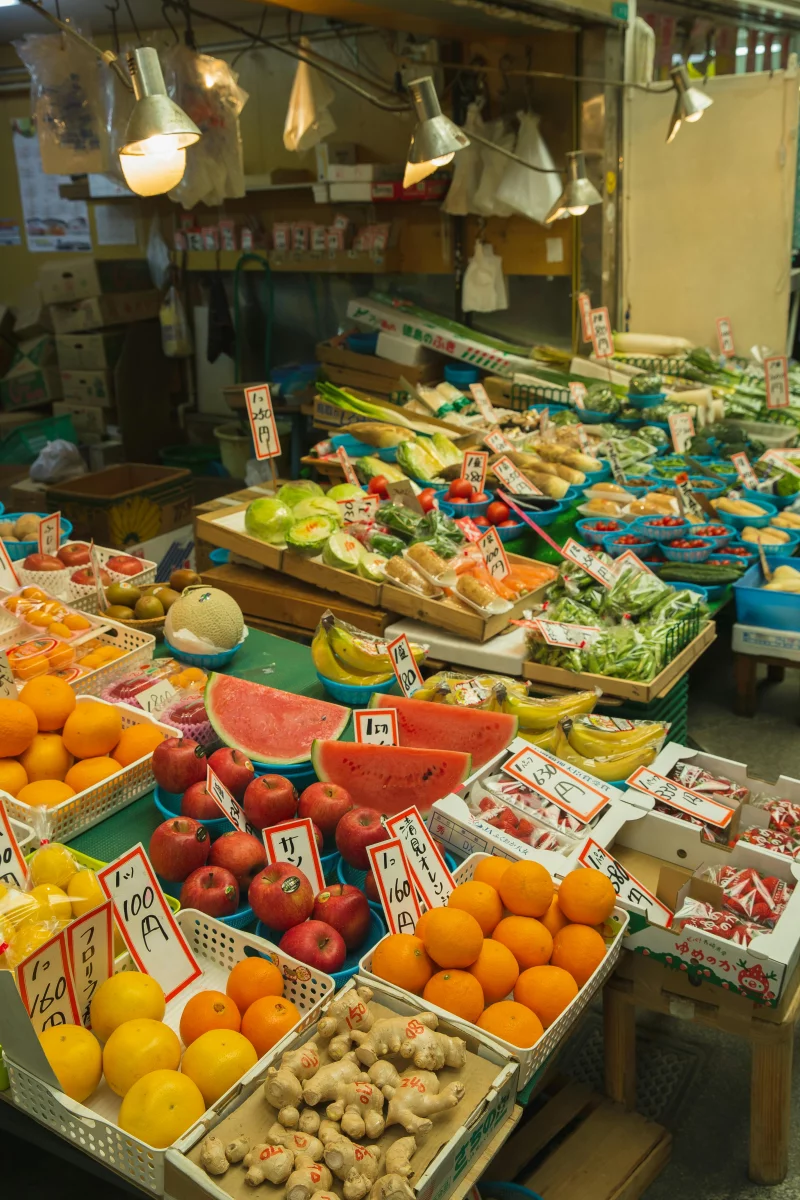A colorful display of fresh fruits and vegetables at an Osaka market stall, highlighting local produce.