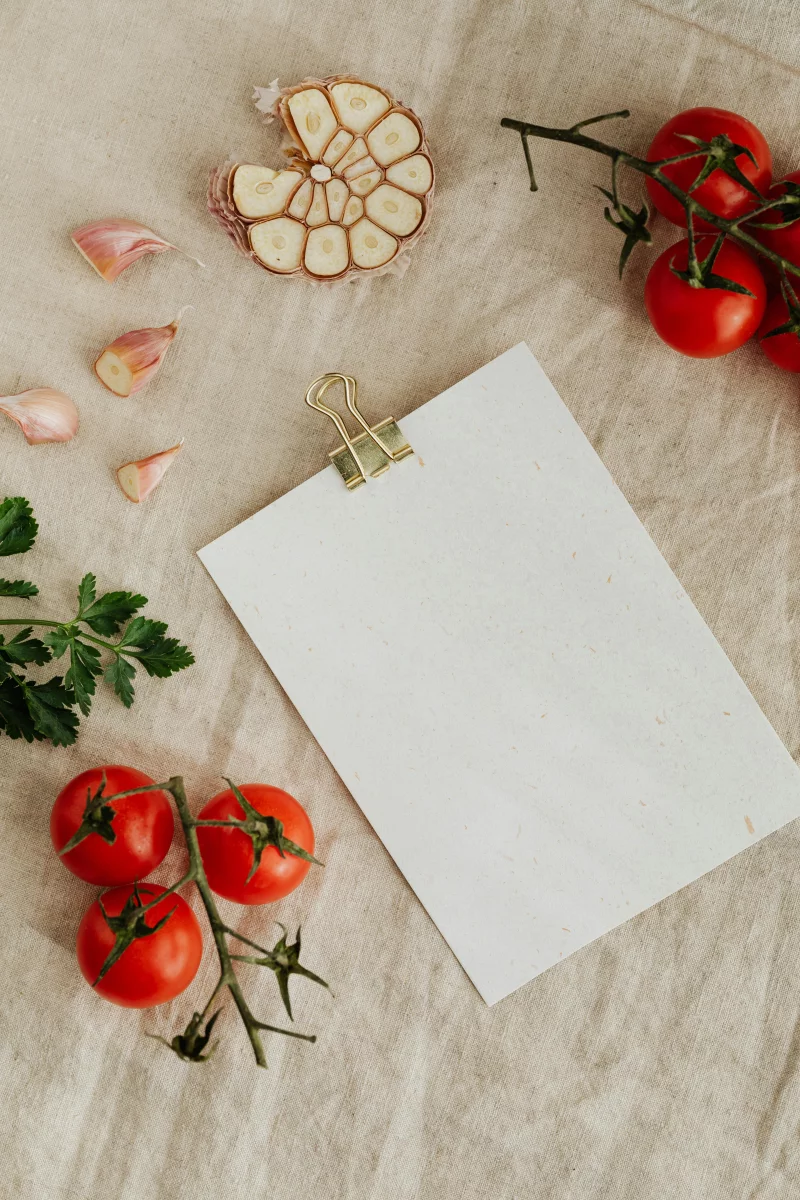 Top view of fresh tomatoes, garlic, and parsley with blank recipe card.