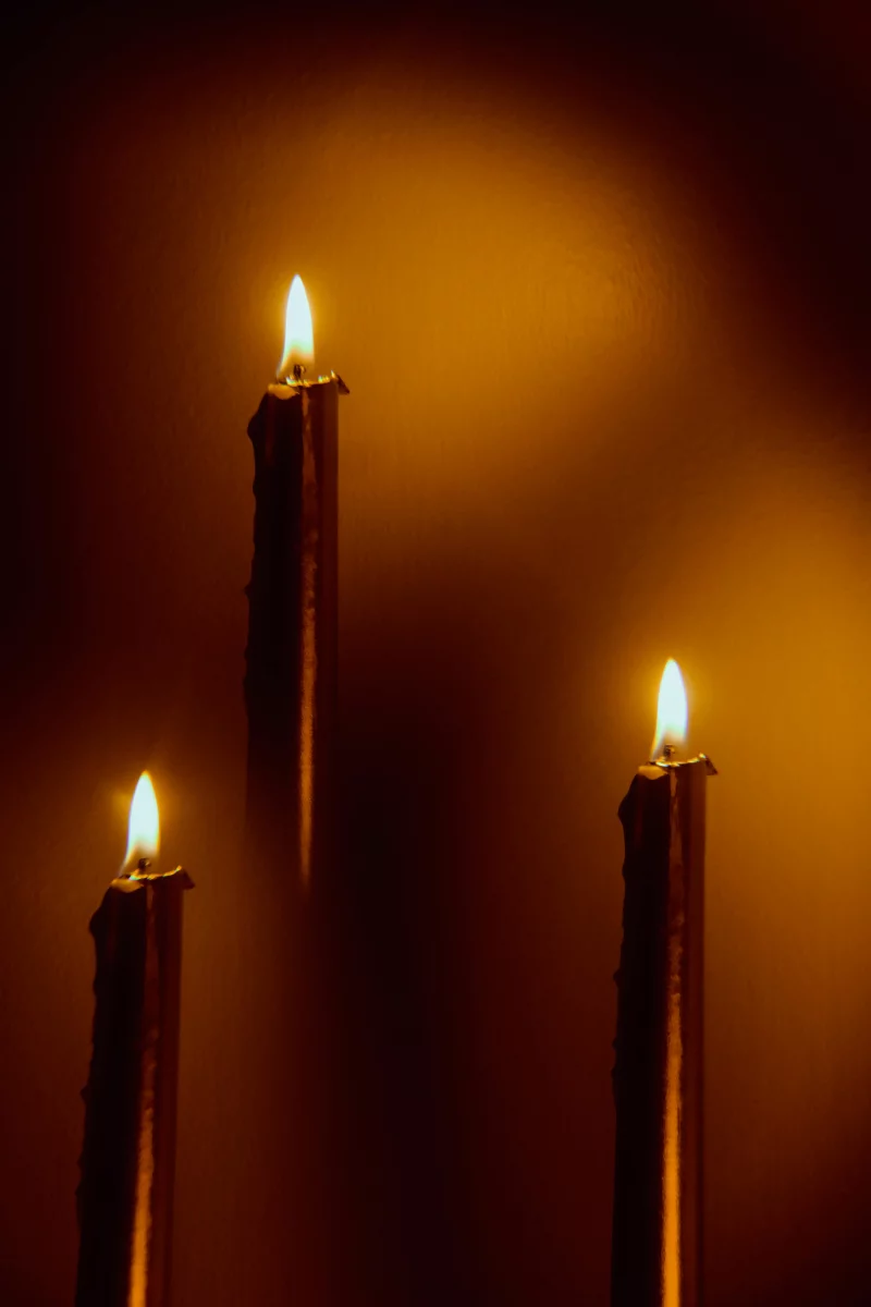 Three vertical candles with warm, glowing flames creating a serene ambiance.