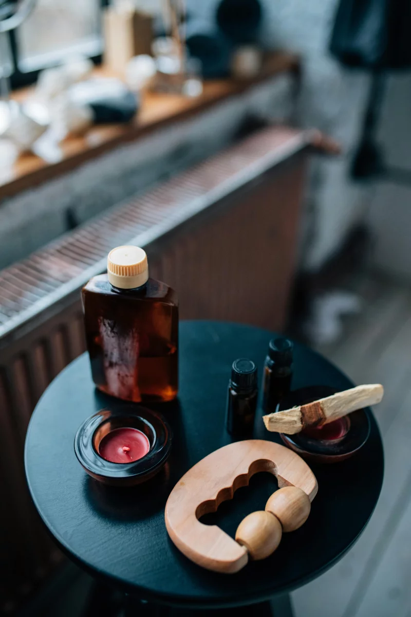 Tranquil aromatherapy scene featuring oils, candle, and massage tools on a table.