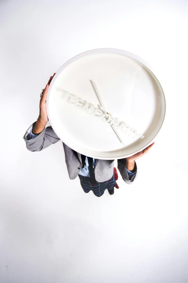 Aerial shot of a person holding a large white clock with a message.