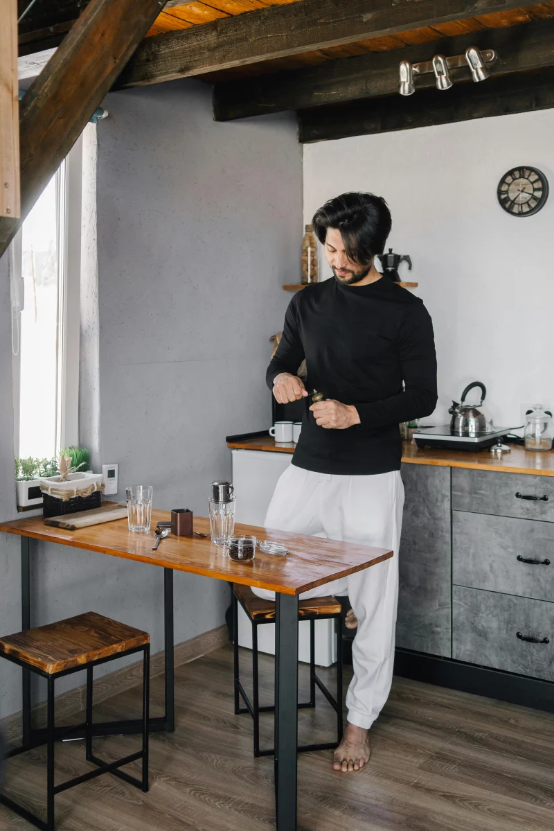 Man enjoying a peaceful morning routine with coffee in a rustic kitchen setting.