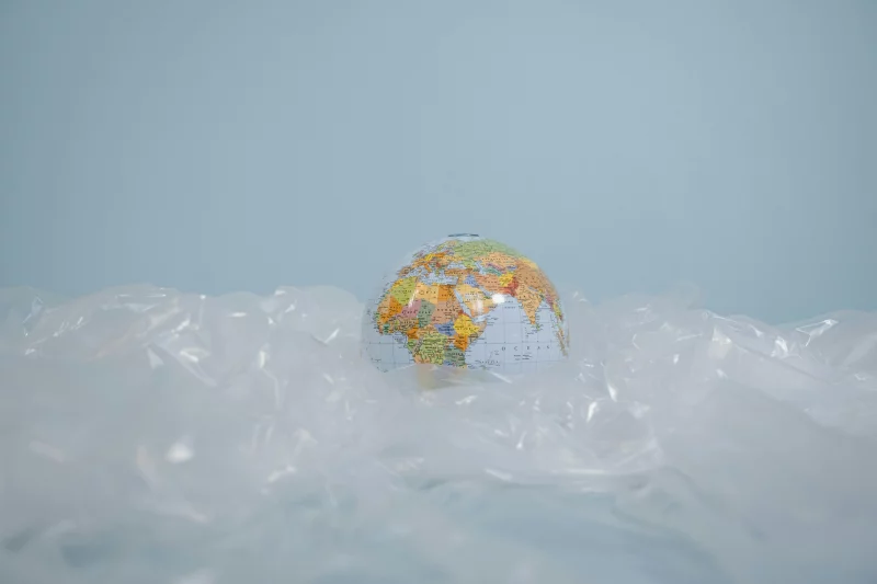 A globe surrounded by plastic, highlighting global environmental pollution issues.