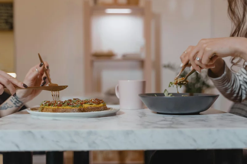 Two people enjoying a casual vegan meal together indoors with a cozy ambiance.