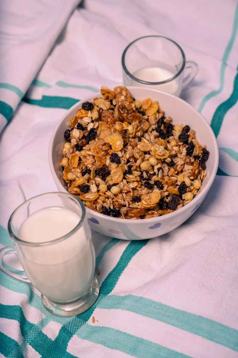 Bowl of muesli with two glasses of milk on a striped cloth for breakfast.