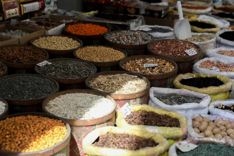 Various nuts and seeds displayed in baskets at an outdoor market, showcasing rich textures and colors.
