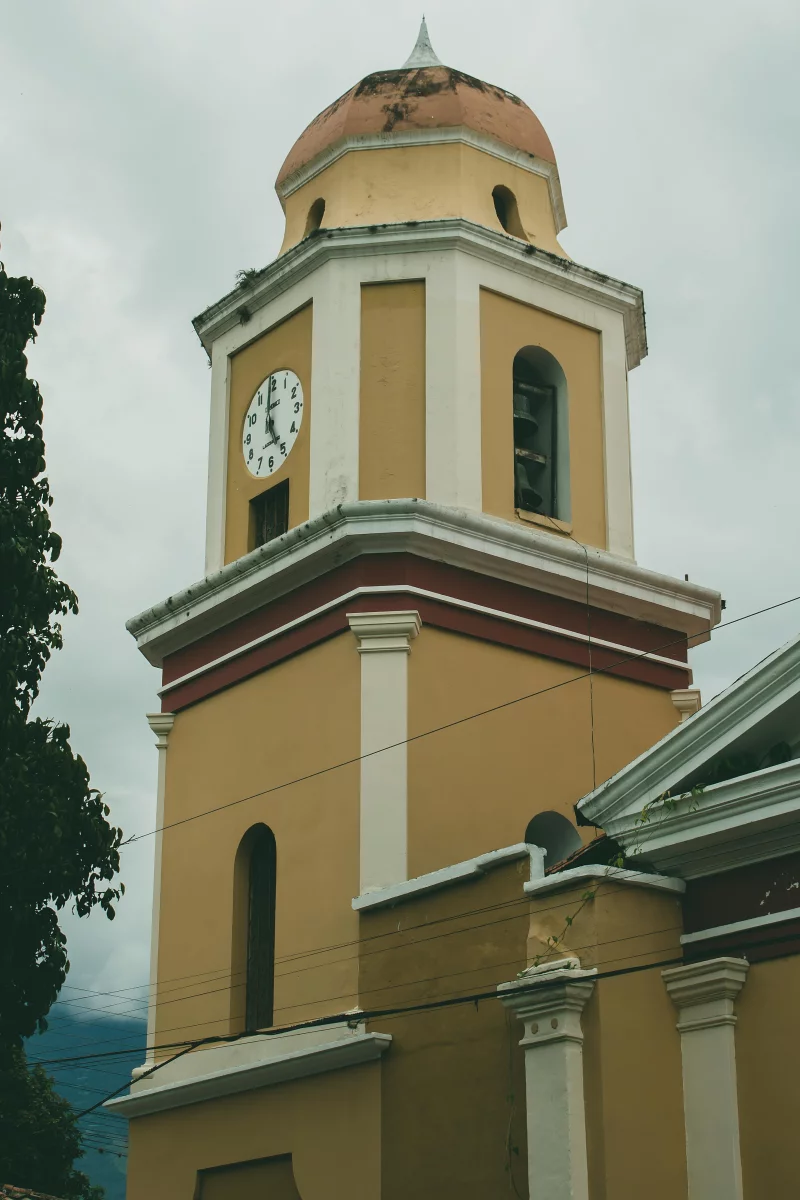 Charming colonial clock tower in Mérida, Venezuela against a cloudy sky.