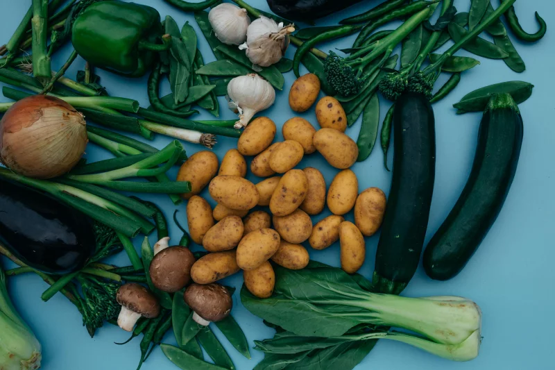 Top view of assorted fresh organic vegetables on a blue background for healthy eating insights.