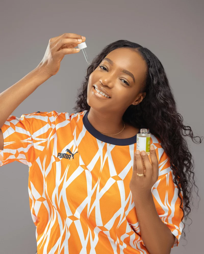 Portrait of a woman applying cosmetic serum, highlighting skincare routine with a bright smile.