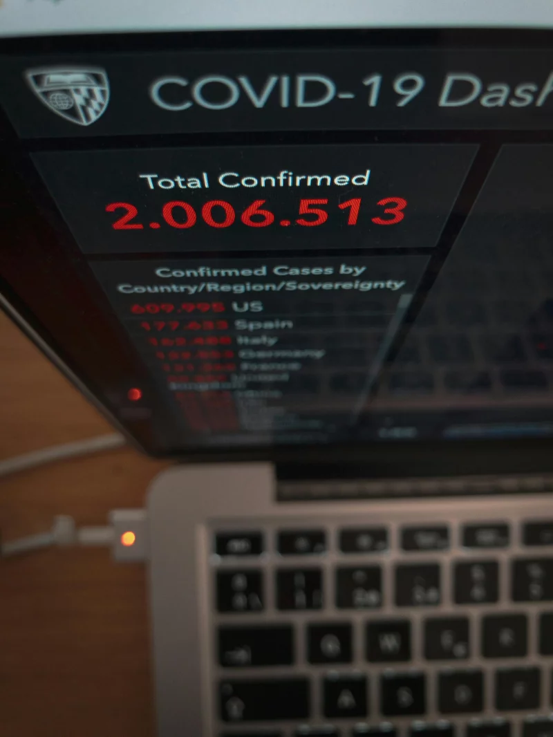 From above of laptop with website demonstrating total amount of COVID 19 cases