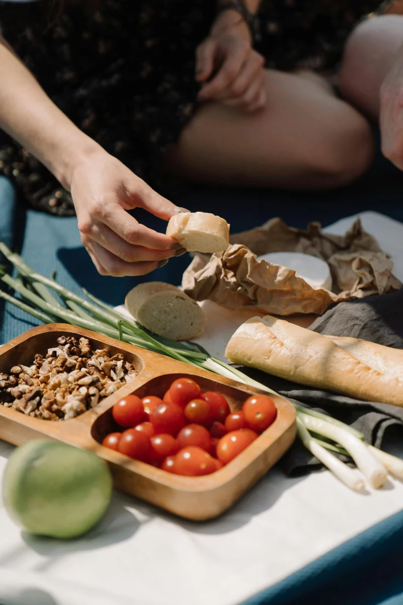 A relaxing outdoor picnic scene with fresh vegetables, bread, and snacks, perfect for a summer day.