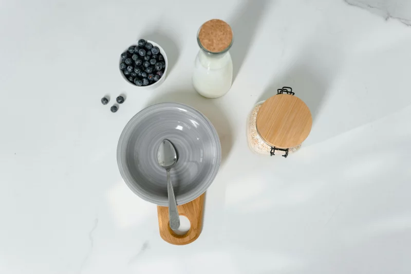 Top view of a healthy breakfast setup with milk, blueberries, and oats.