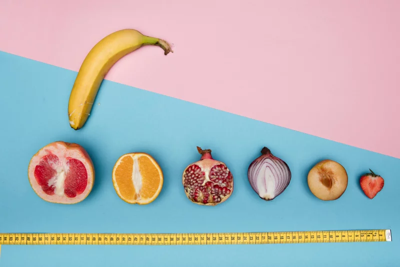 Colorful fruits and vegetables including banana, citrus, and onion creatively arranged with a measuring tape.