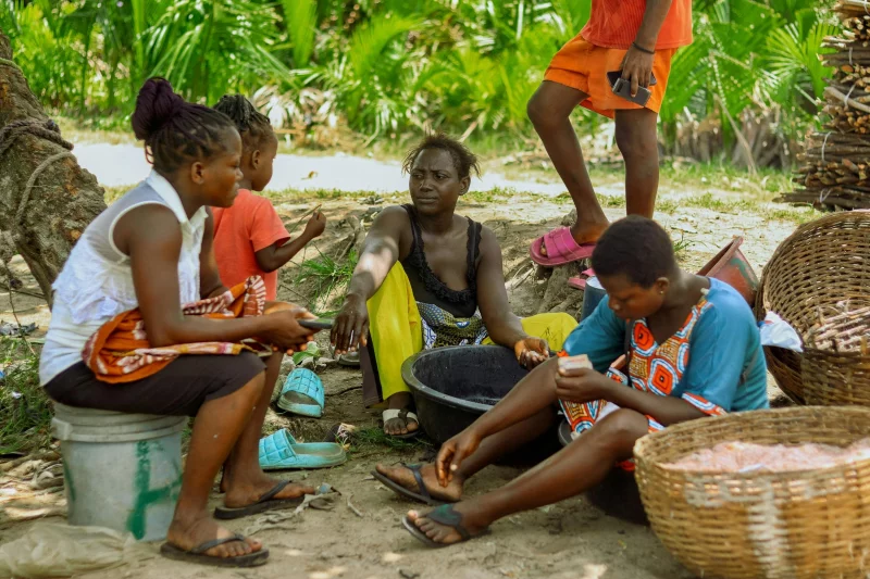 A family engaged in daily chores outdoors, surrounded by greenery and baskets.