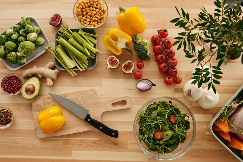 Top view of fresh vegetables and ingredients on a wooden table, perfect for healthy cooking inspiration.