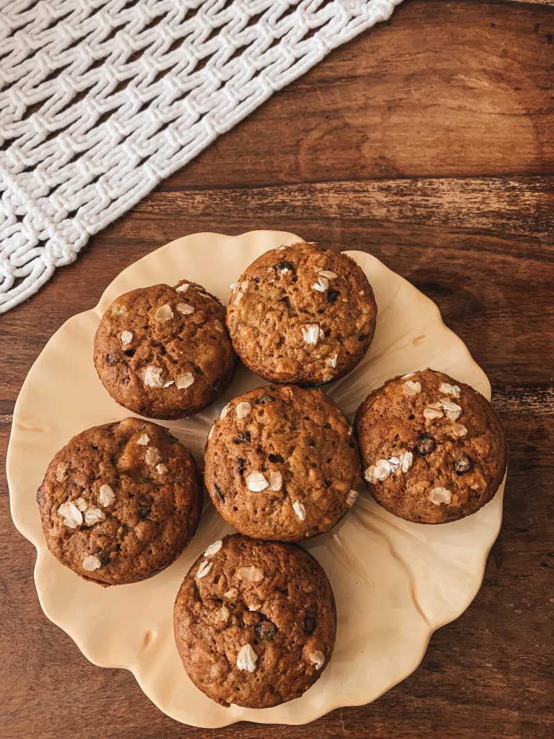Freshly baked oatmeal raisin muffins served on a ceramic plate, perfect for a cozy snack setting.