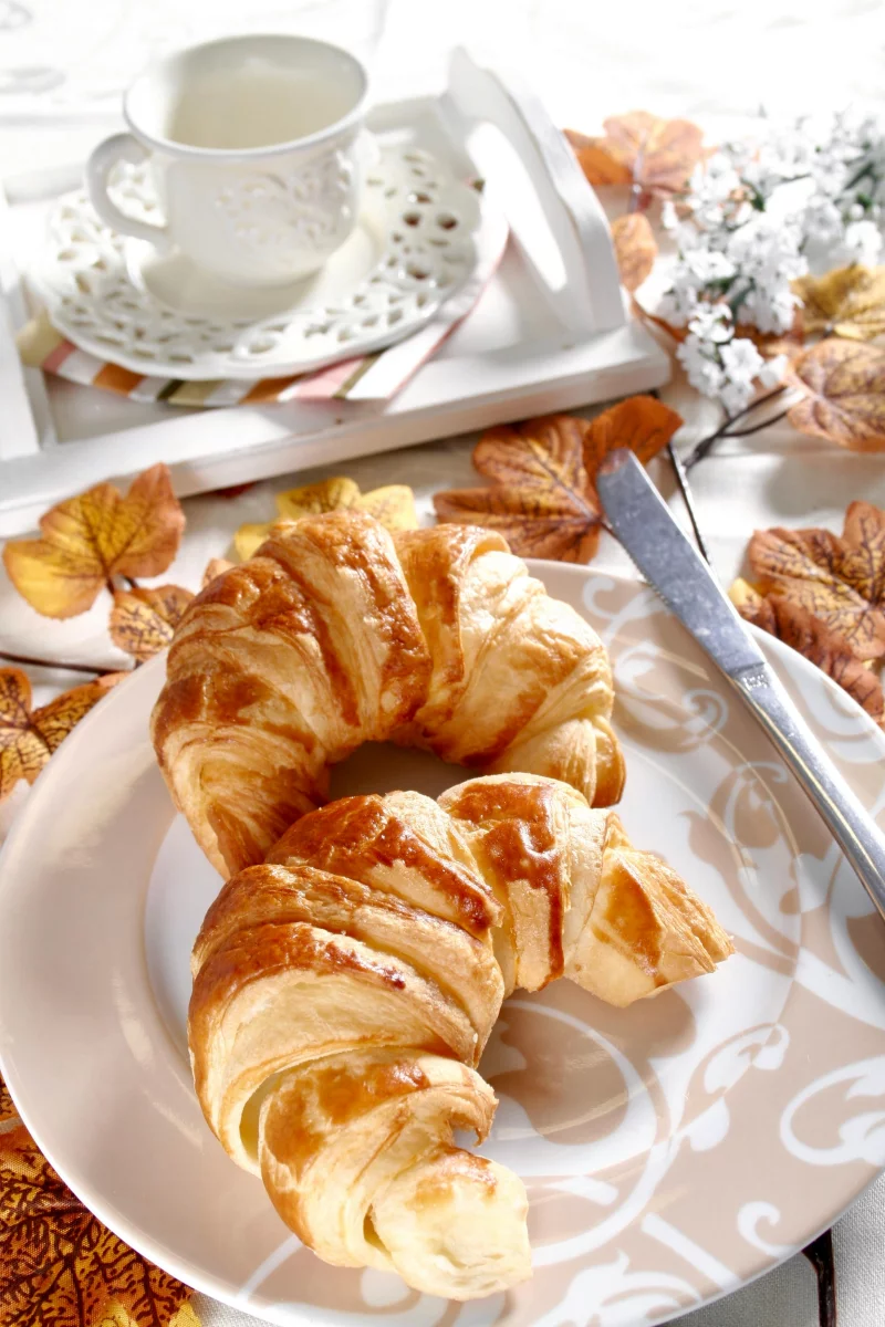 Delicious fresh croissants served with a cup of coffee, perfect for a cozy fall breakfast.