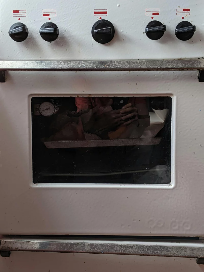 Detailed view of a kitchen oven door showing reflection with control knobs visible.