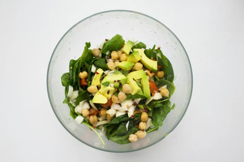 Fresh spinach salad featuring avocado and chickpeas, perfect for healthy eating.