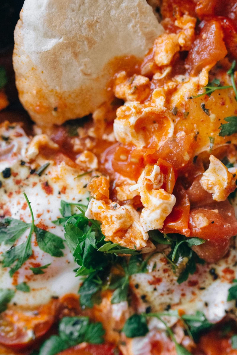 Delicious shakshuka served with pita, featuring eggs, tomatoes, and herbs for a fresh Middle Eastern meal.