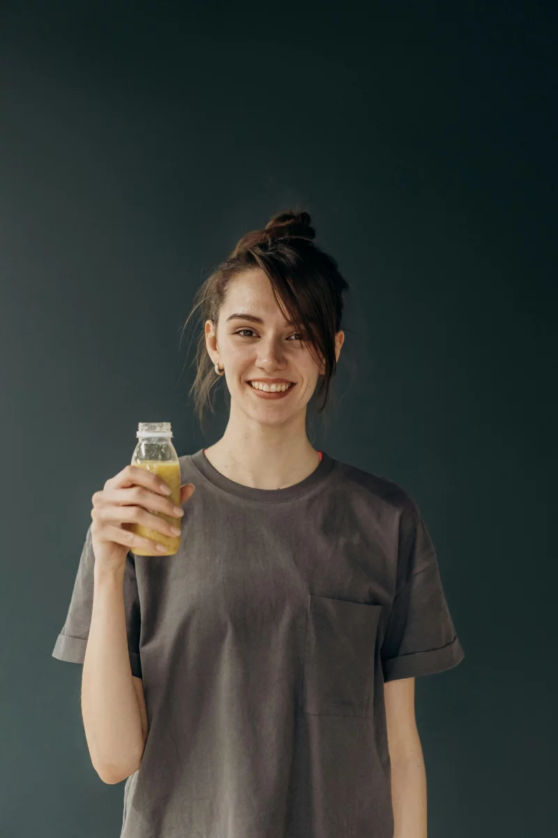 A cheerful woman enjoying a refreshing healthy drink, emphasizing wellness and lifestyle.