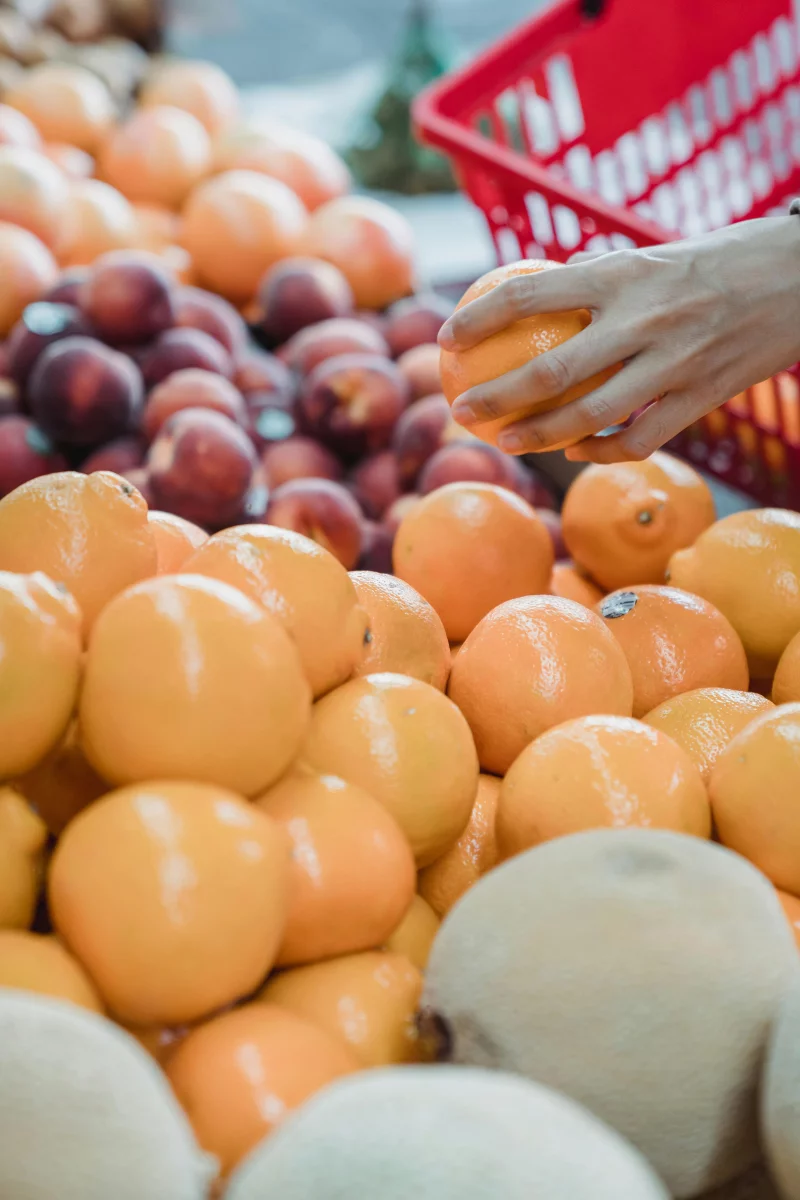Close-up of a hand picking oranges at a vibrant local market.