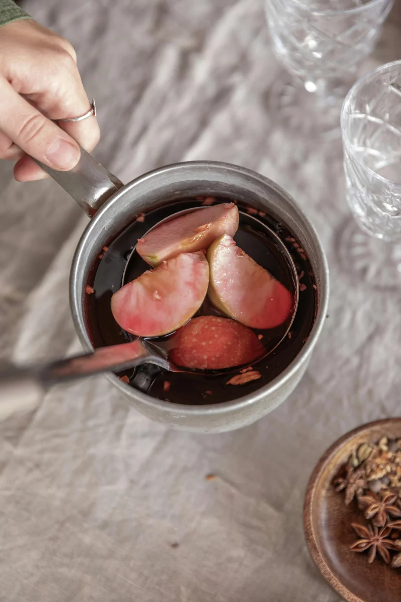 Warm mulled wine with apple slices and spices for a cozy beverage experience.