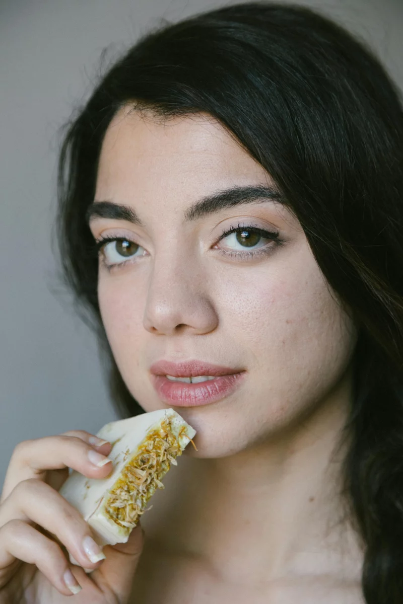 Close-up portrait of a woman holding organic bar soap, highlighting natural beauty skincare.