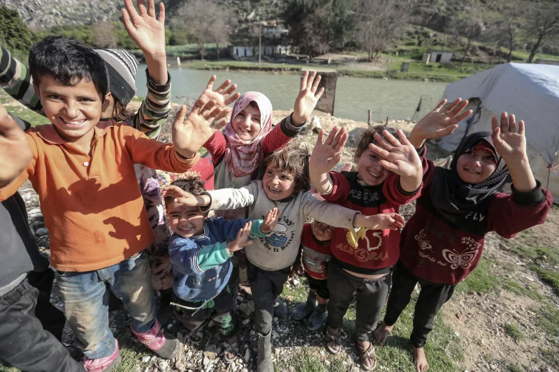 Happy children waving enthusiastically in an outdoor setting, showcasing joy and unity.