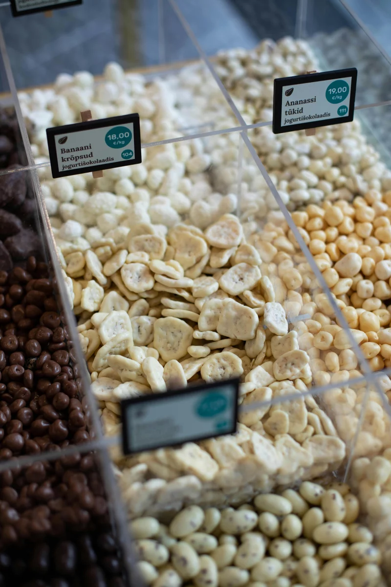 Variety of snacks including chocolate and dried fruits in market display bins.