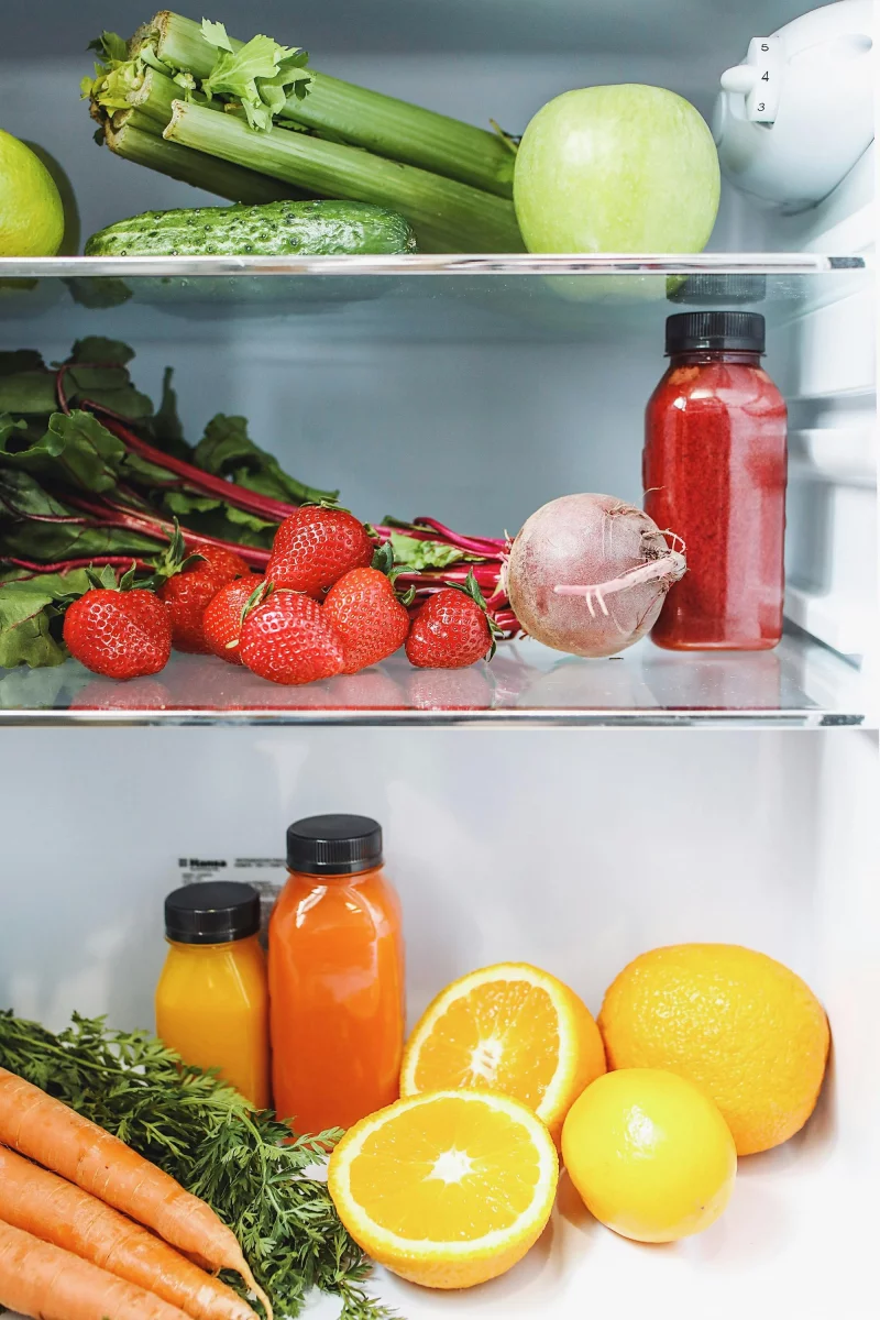 Colorful vegetables and juices in a fridge, showcasing healthy and fresh ingredients.