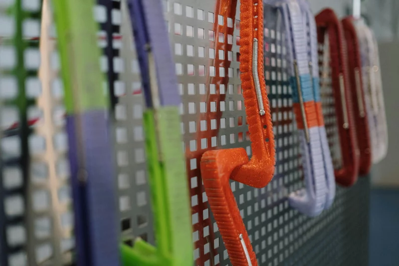 Vibrant clothes hangers displayed on a perforated wall with selective focus.