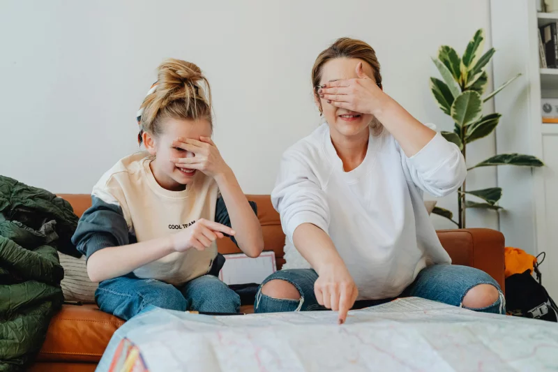 A mother and daughter planning a fun trip at home, pointing at a map
