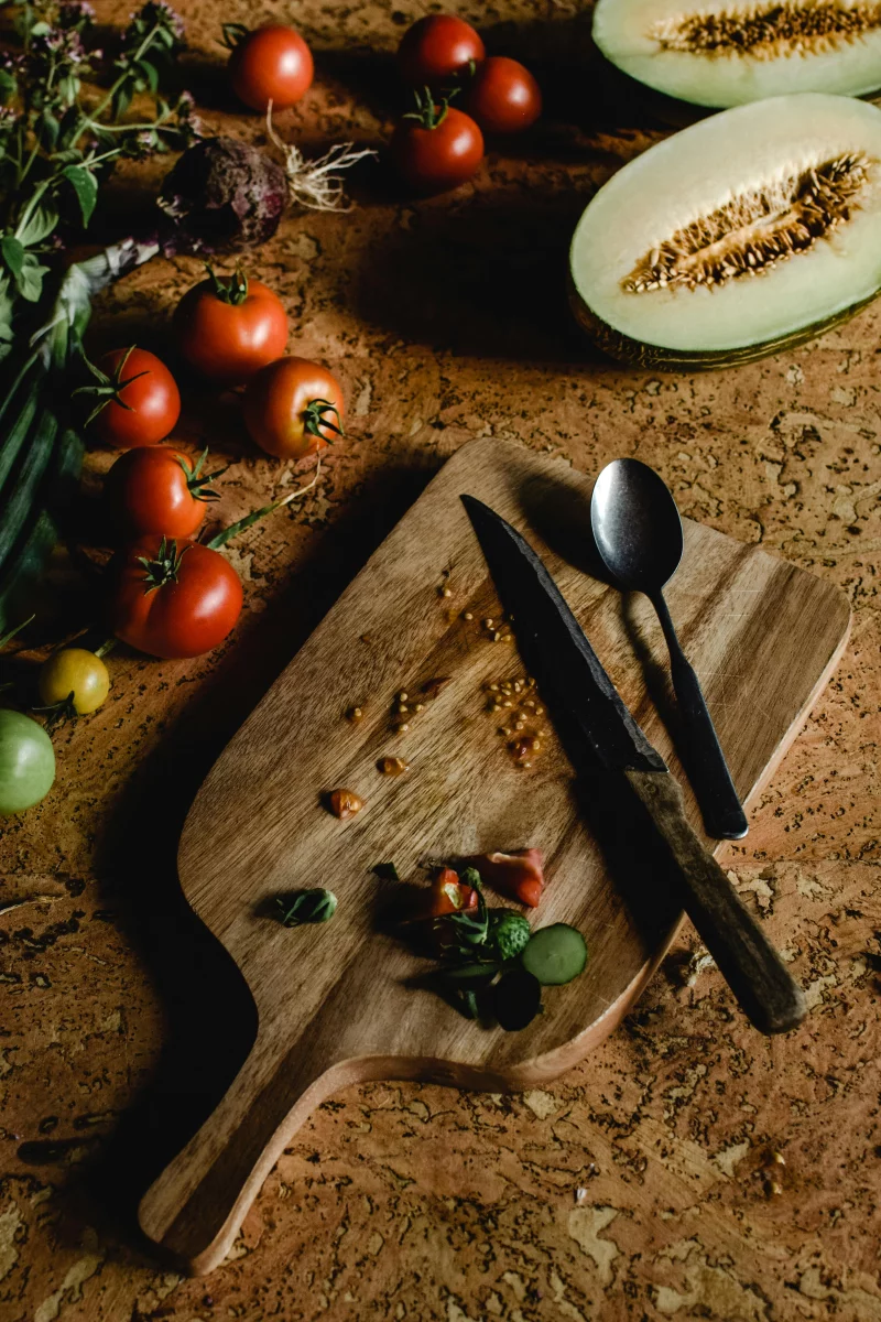 Wooden chopping board with fresh tomatoes and melon slices, embodying a rustic kitchen vibe.
