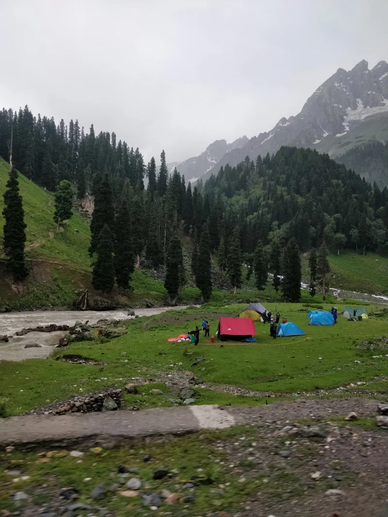 Picturesque camping scene with tents in a lush mountain valley.